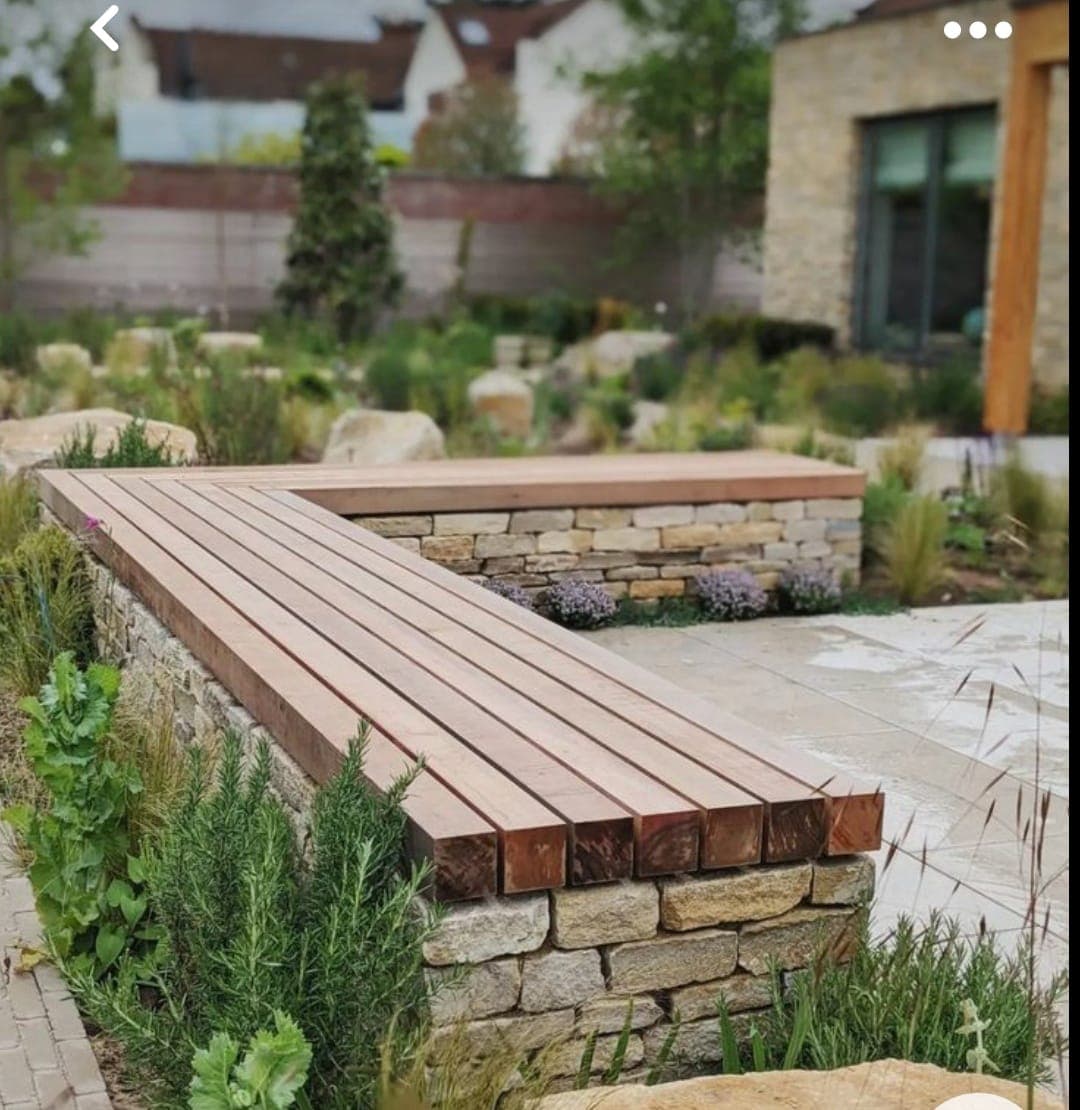Stone retaining wall with cedar bench seating surrounded by native plants